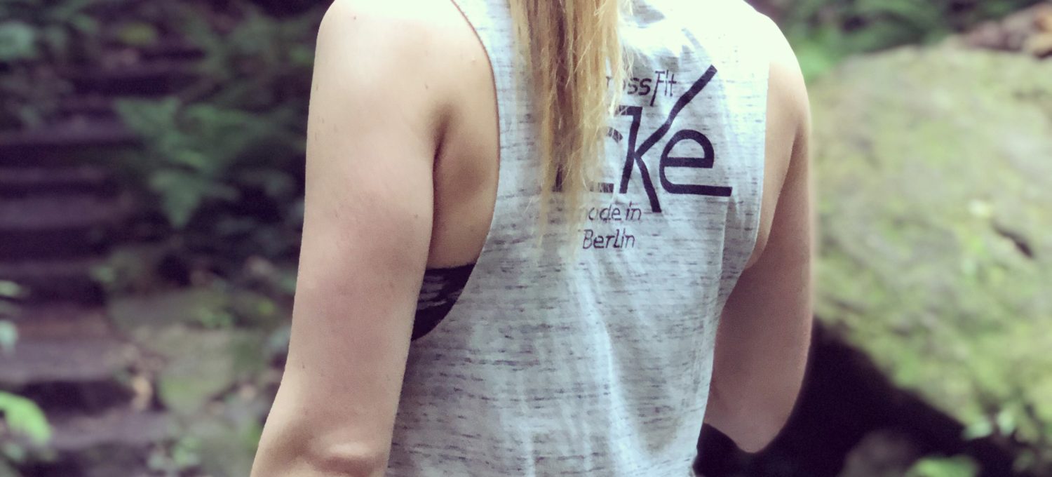 strong is the new skinny, picture of a strong female body's back in the woods.